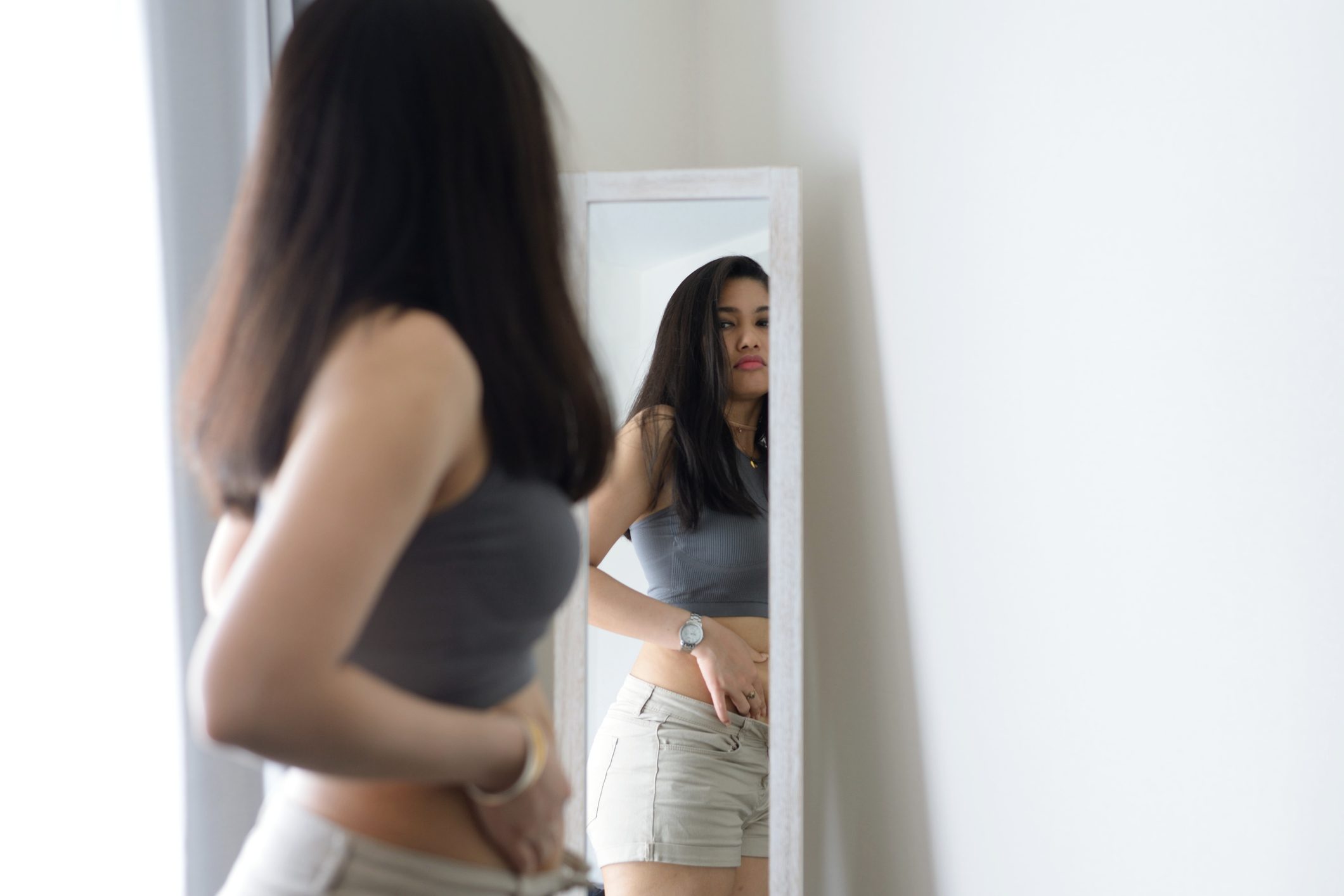 woman looking in mirror not pleased with her reflection