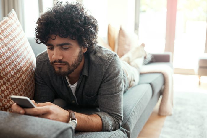 young man laying on couch looking at phone