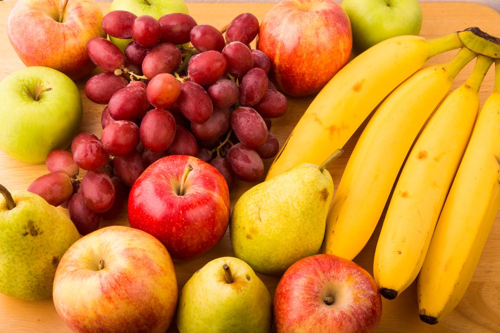 Closeup of fresh bananas, pears, apples and grapes on a wood table