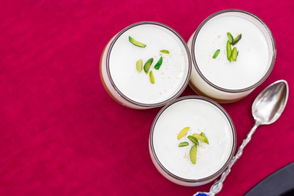 Three small jars of the panna cotta with pistachio on a red napkin. Top view, selective focus.