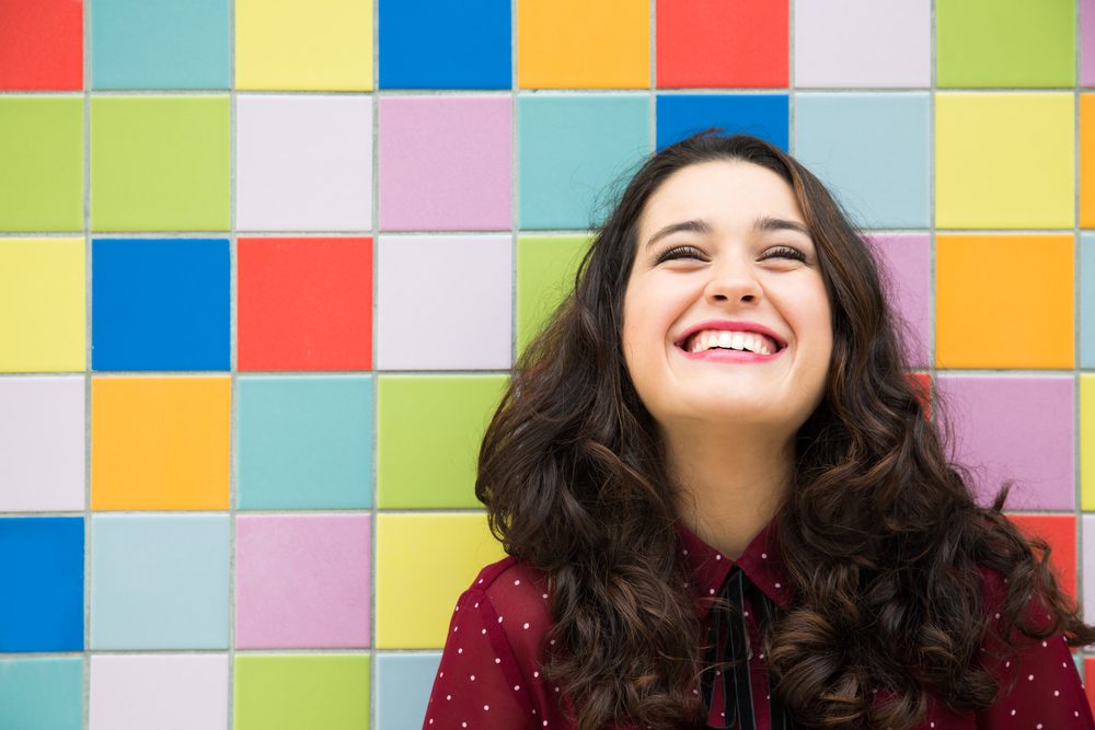 Happy girl laughing against a colorful tiles background. Concept of joy