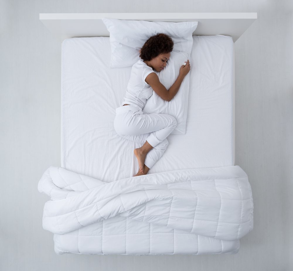 Beautiful african american woman lying in bed and sleeping, top view