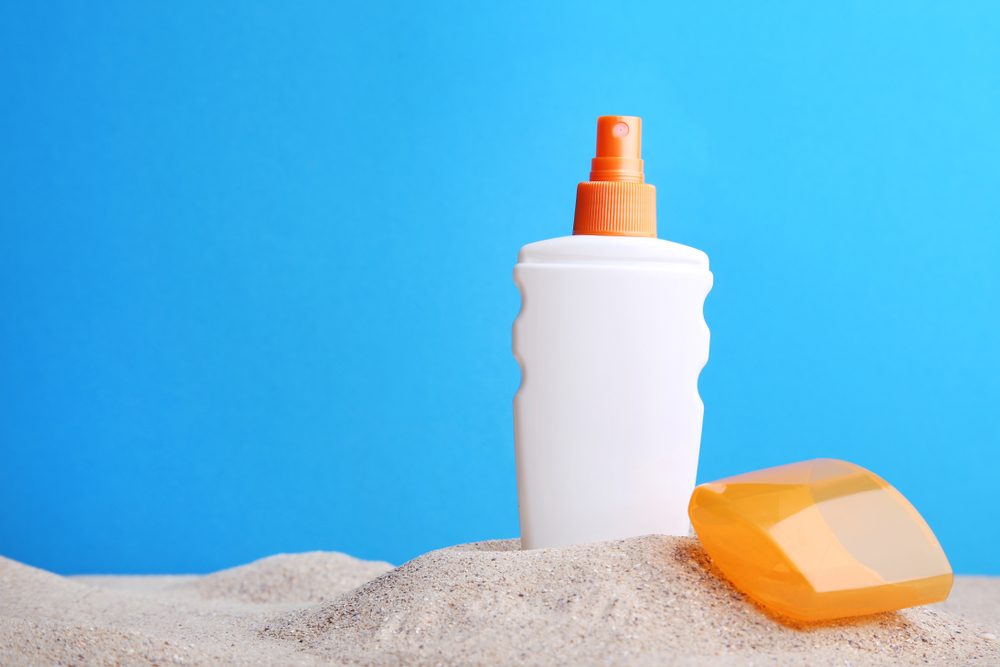 sunscreen bottle propped in sand