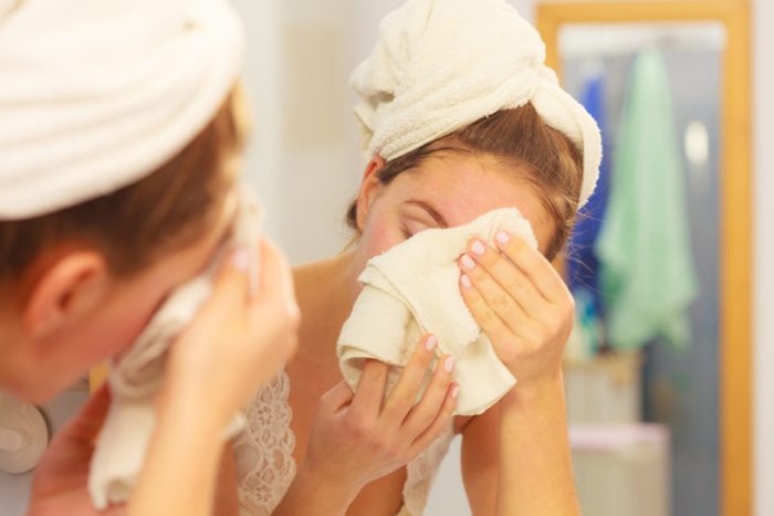 Woman cleaning washing her face with clean water in bathroom. Girl taking care of her complexion. Morning hygiene. Skincare treatment