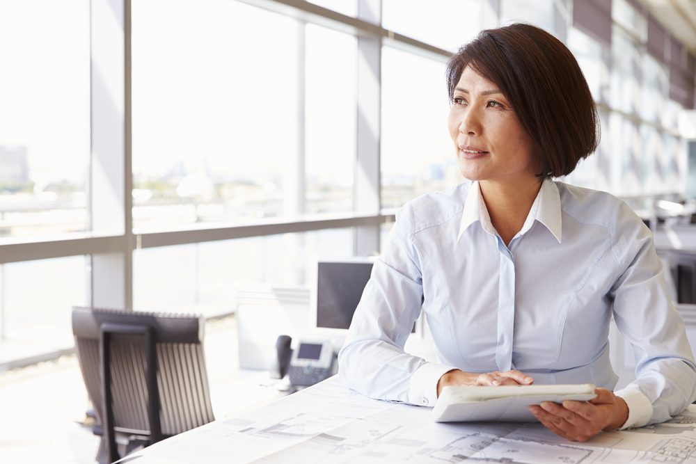 Female architect using tablet computer, looking away