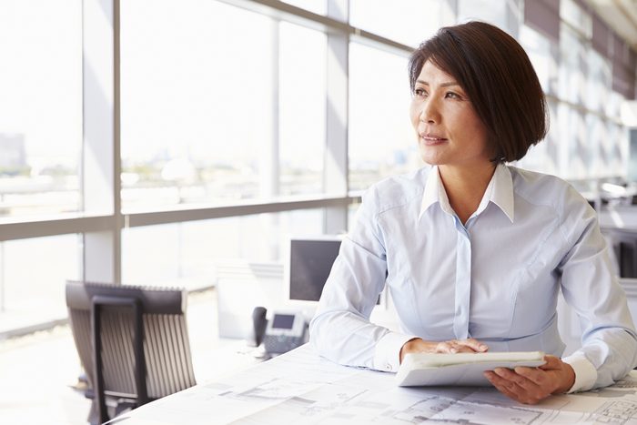 Female architect using tablet computer, looking away