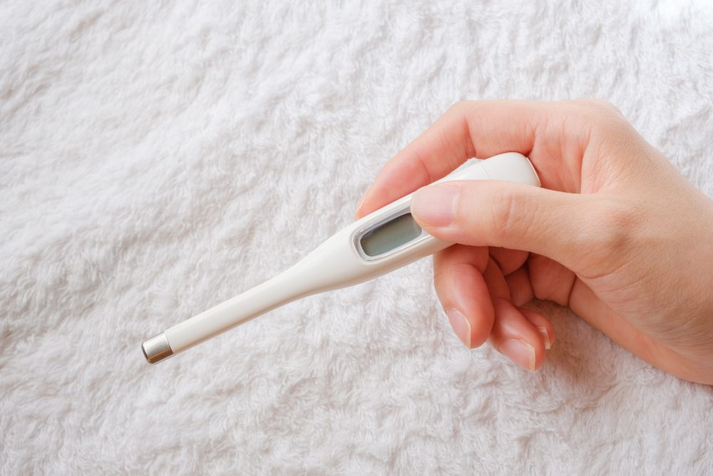 person looking at digital clinical thermometer