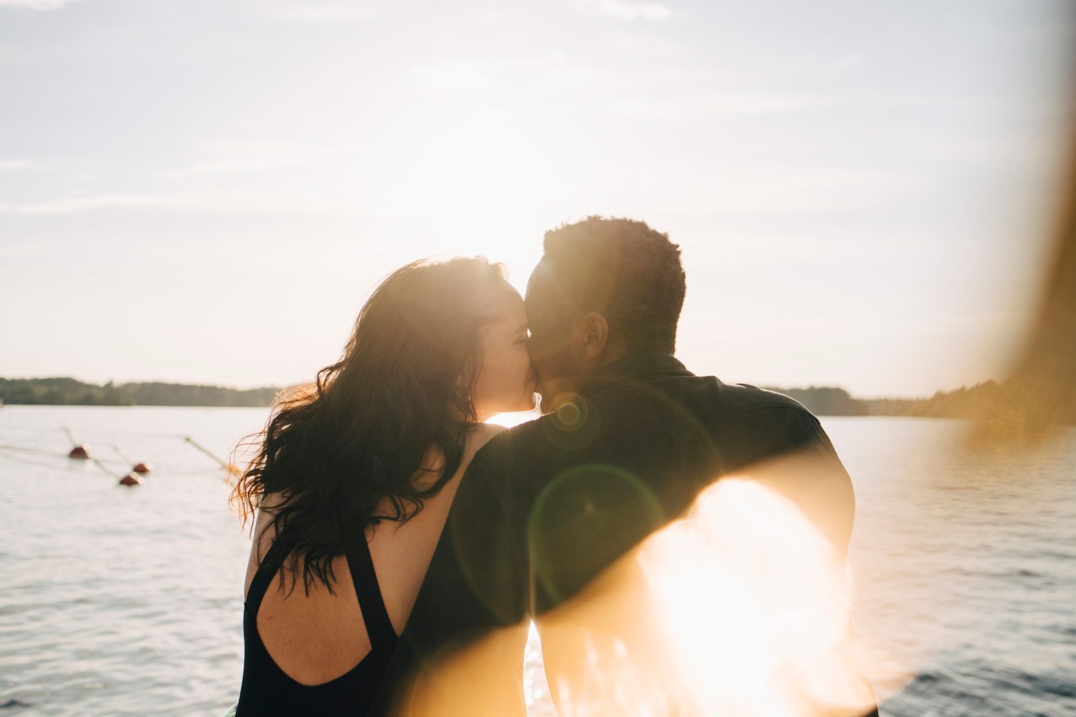 rear view of couple kissing while sitting on a dock