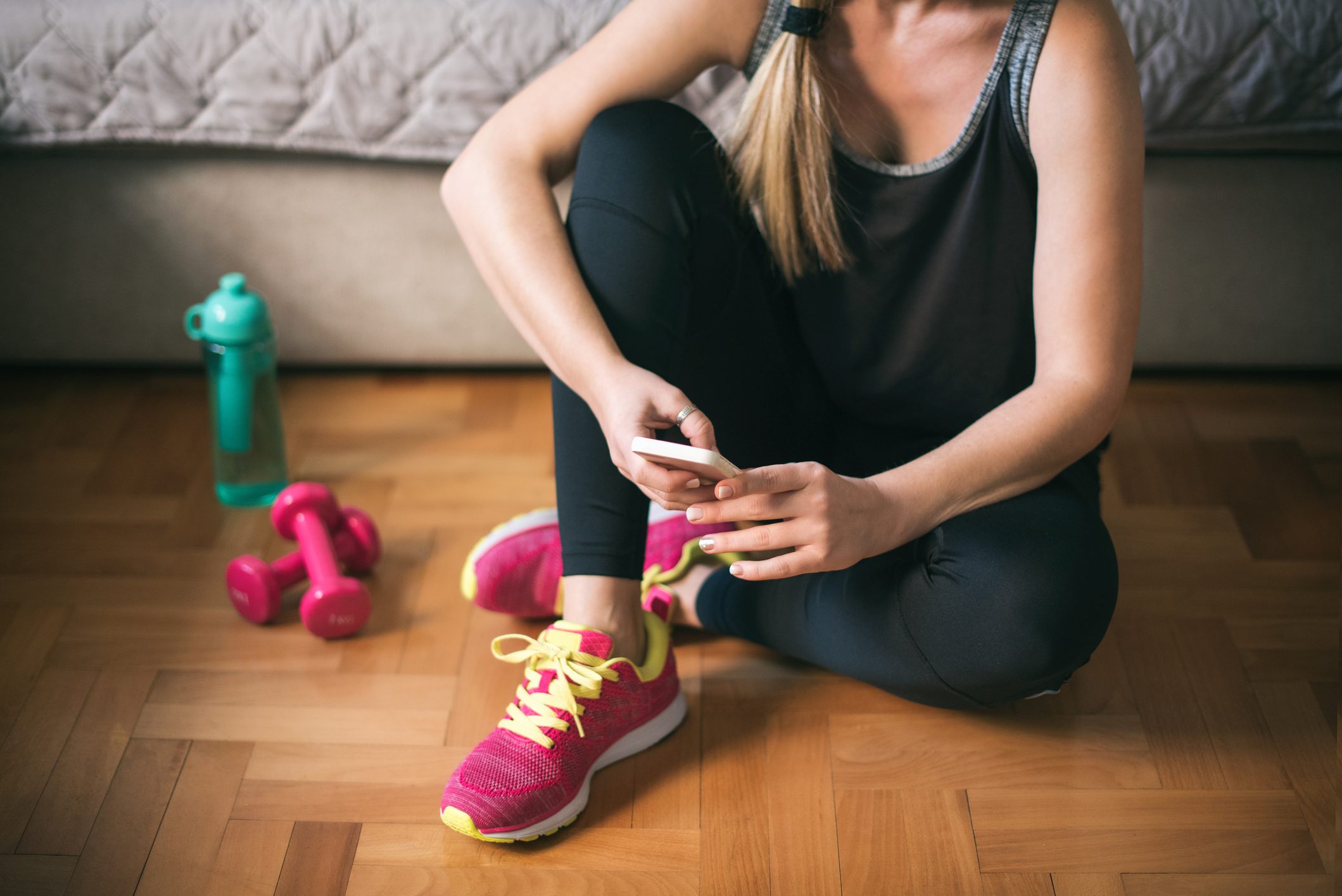 young woman looking at smartphone before workout