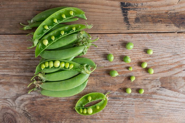 Pile of Sugar snap peas on the wooden background. Top view.