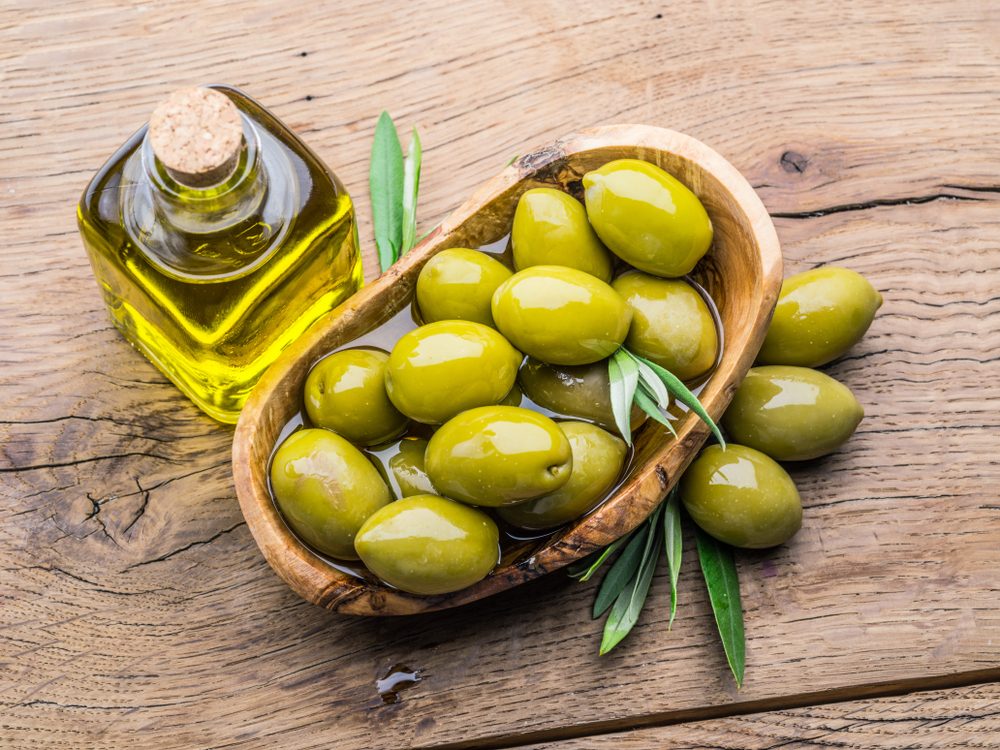 Olives and bottle of olive oil on the wooden table.