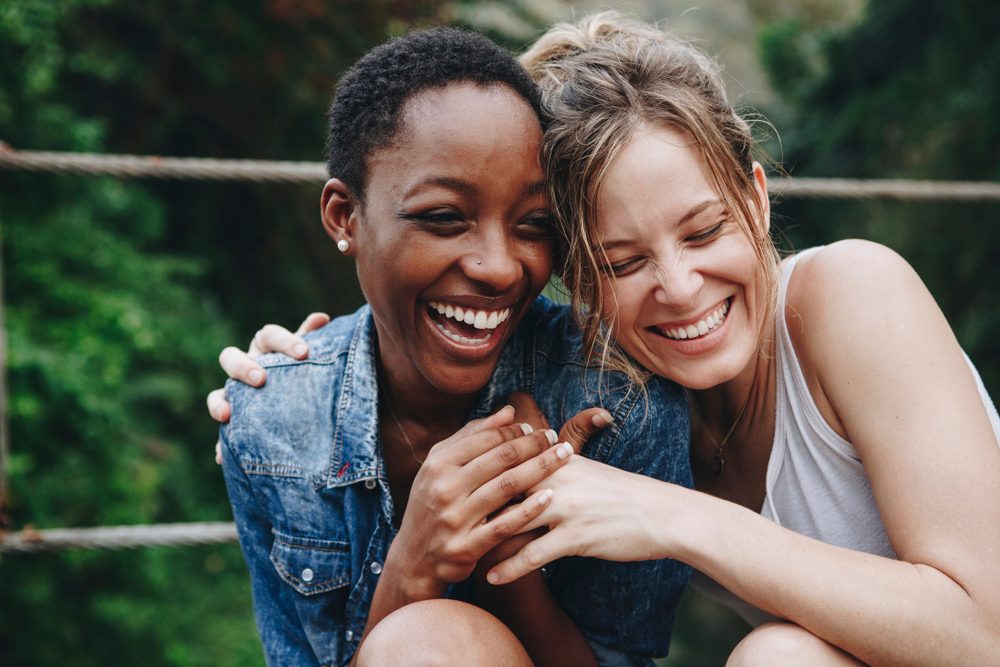 two happy women, laughing and hugging