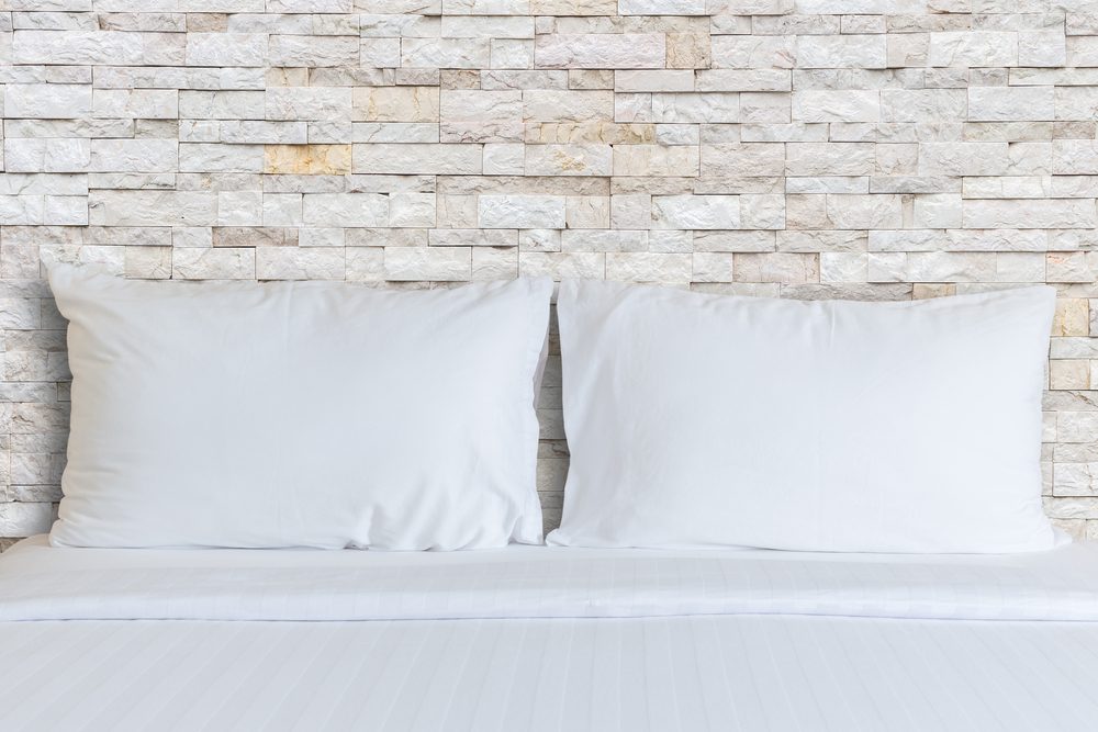 Close up white bedding sheets and pillow in hotel room.