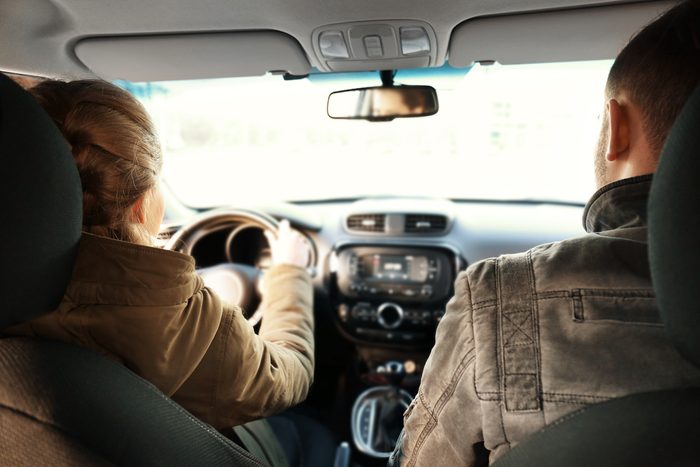 Young woman driving car with man in passenger seat