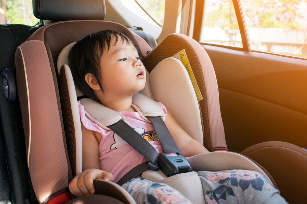 Toddler girl sitting in her car seat, looking outside the window.