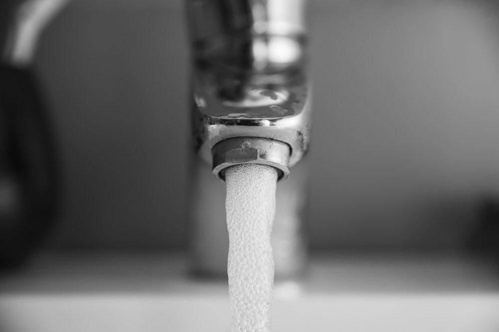 Running water/Close up of a water jet with air bubbles flowing from a water tap in a bathroom sink.