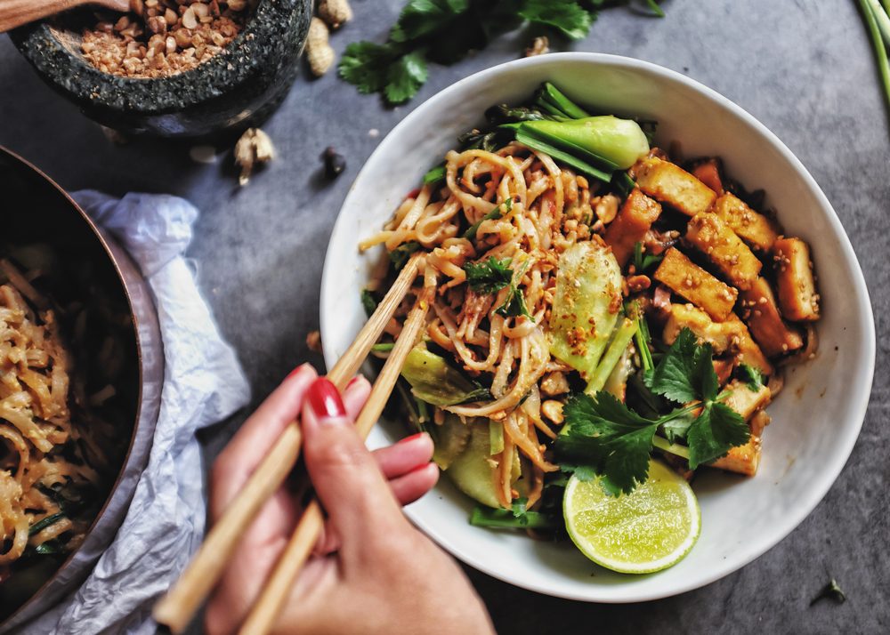  Udon with Padthai sauce, Healthy Vegetarian/vegan menu; Padthai noodle with smoke tofu and mixed vegetable - chinese baby Bok Choy , garlic chive, shallot and crushed peanut topping. chopstick hold.