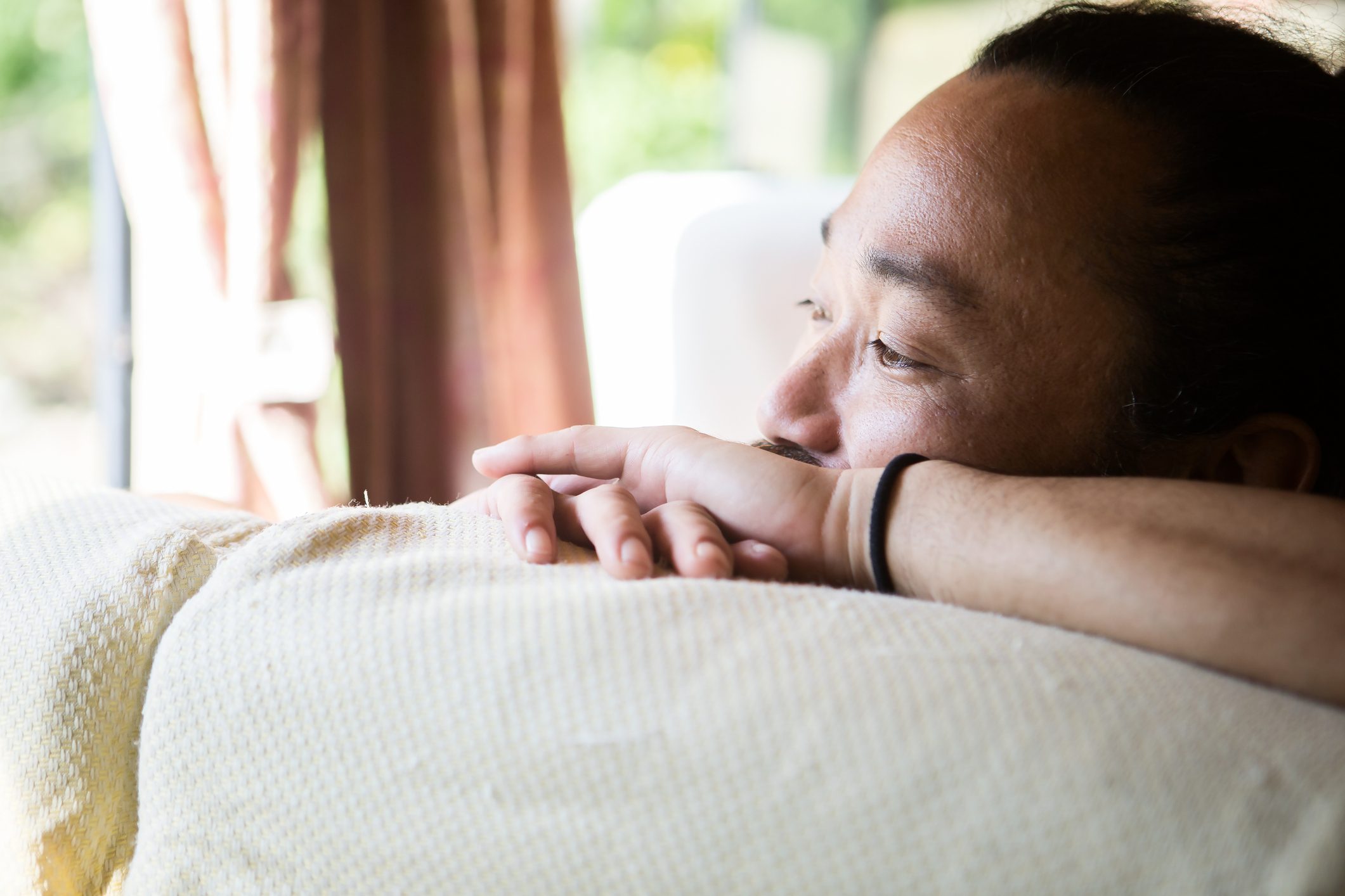 stressed man looking out window at home