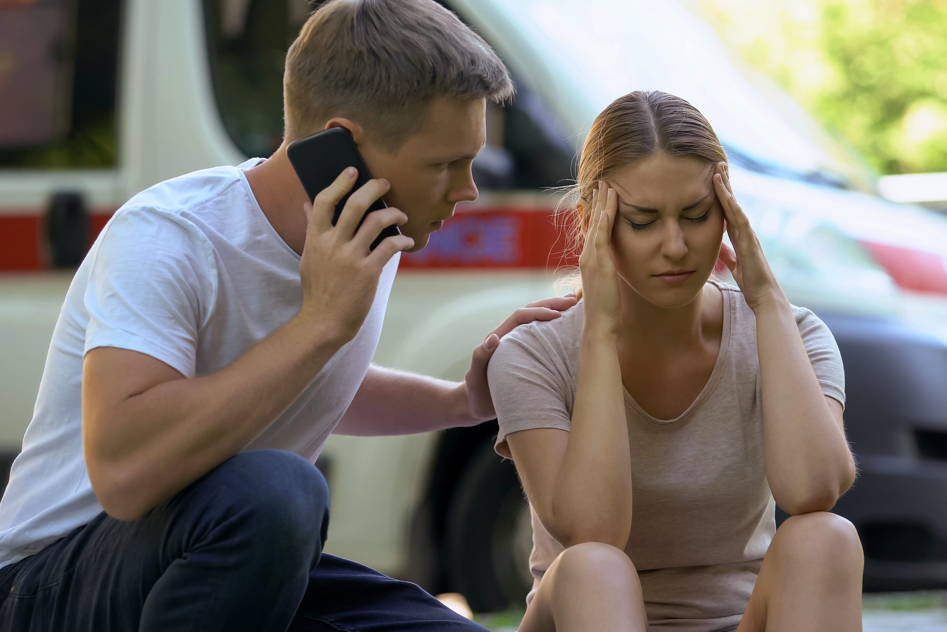 man calling an ambulance for woman in pain