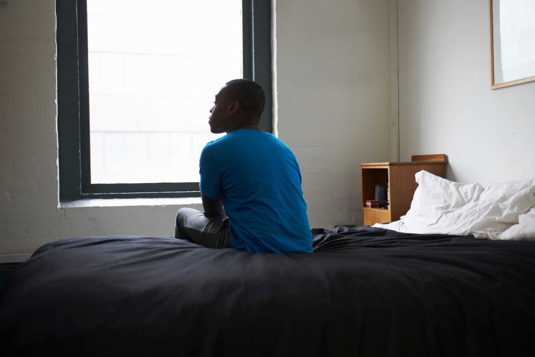 man sitting on his bed alone