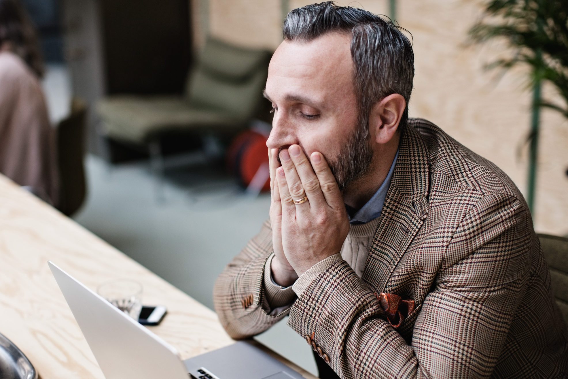 upset businessman looking at laptop