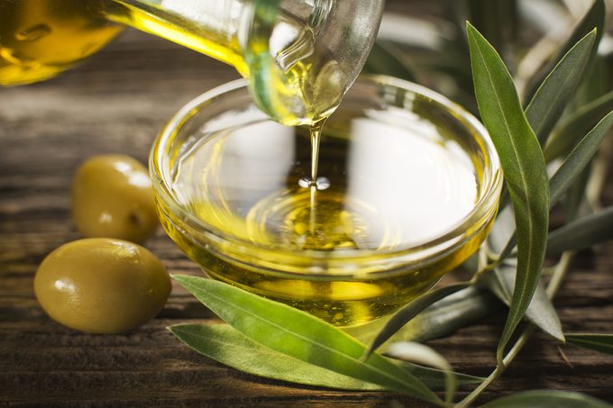 Bottle pouring virgin olive oil in a bowl close up