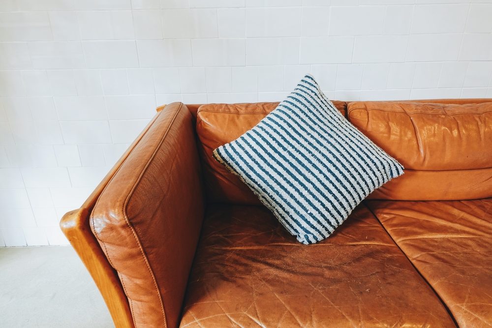 Vintage brown leather couch with pillow in living room