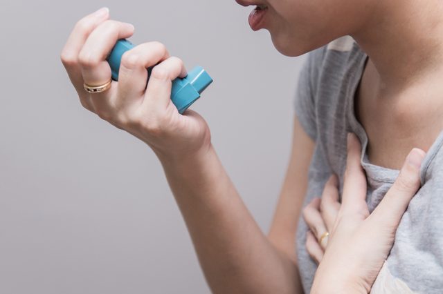 Asian woman using a pressurized cartridge inhaler extended pharynx, Bronchodilator