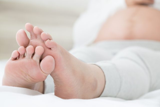 Southeast asian pregnant women with swelling feet, pain foot and lying on bed in the room. Swollen feet and fetal poisoning or toxicity concept