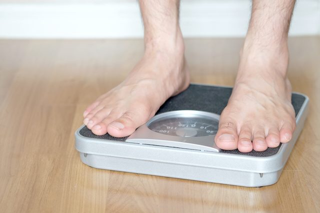 Legs of men standing on scales weight. Concept of health and weight loss.