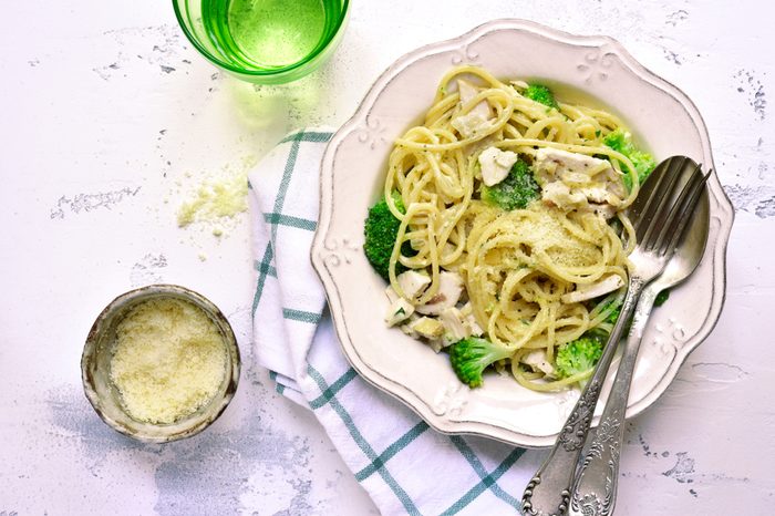 Spaghetti with broccoli, chicken, and Parmesan in a vintage white bowl .