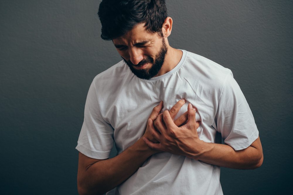 People, healthcare and problem concept - close up of man suffering from heart ache over gray background