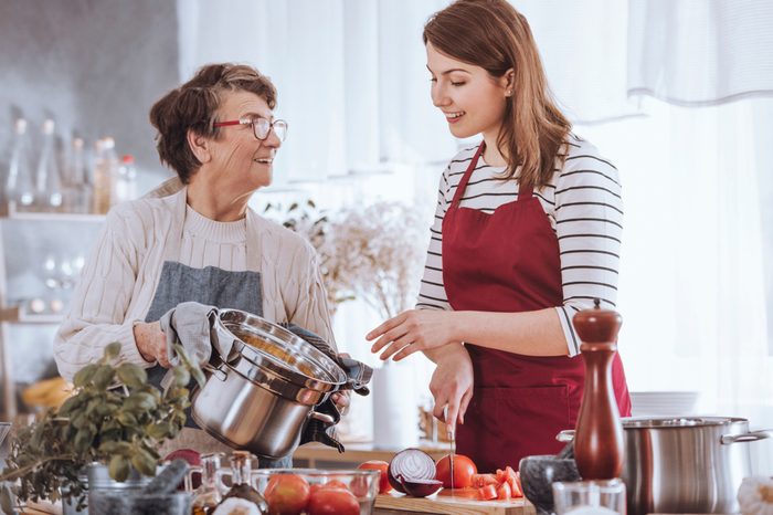 Grandma and granddaughter cooking tomato soup in the kitchen.