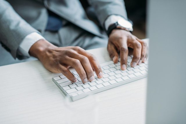 man's hands on computer keyboard