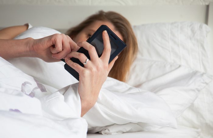 woman using smartphone in bed