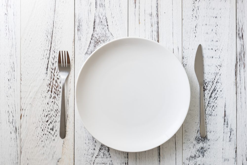 Round Plate with utensils on white wooden table background