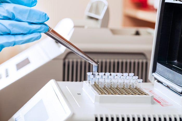 Gloved hand of technician loading test tubes with sampled DNA for polymerase chain reaction