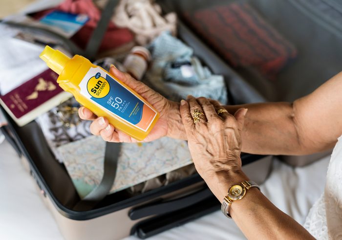 Senior woman applying sunscreen on her arm