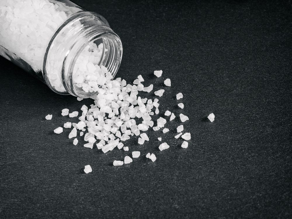 A tipped over shaker spilling salt crystals.
