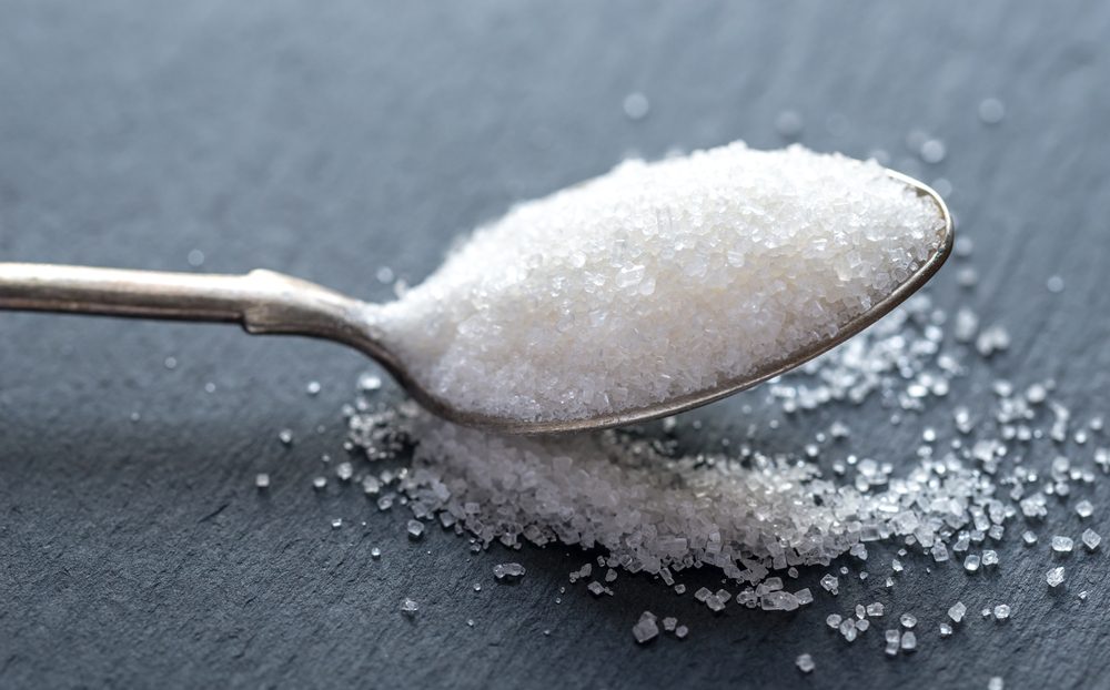 Spoon with white sugar on the dark background