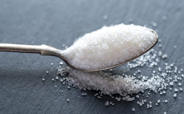 Spoon with white sugar on the dark background