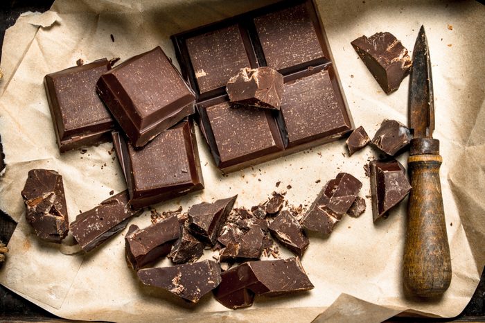 Chocolate squares and shavings with knife on paper