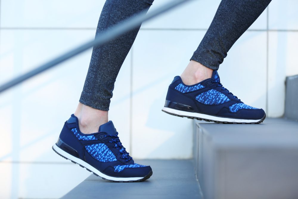 Sports woman legs in sneakers on stairs