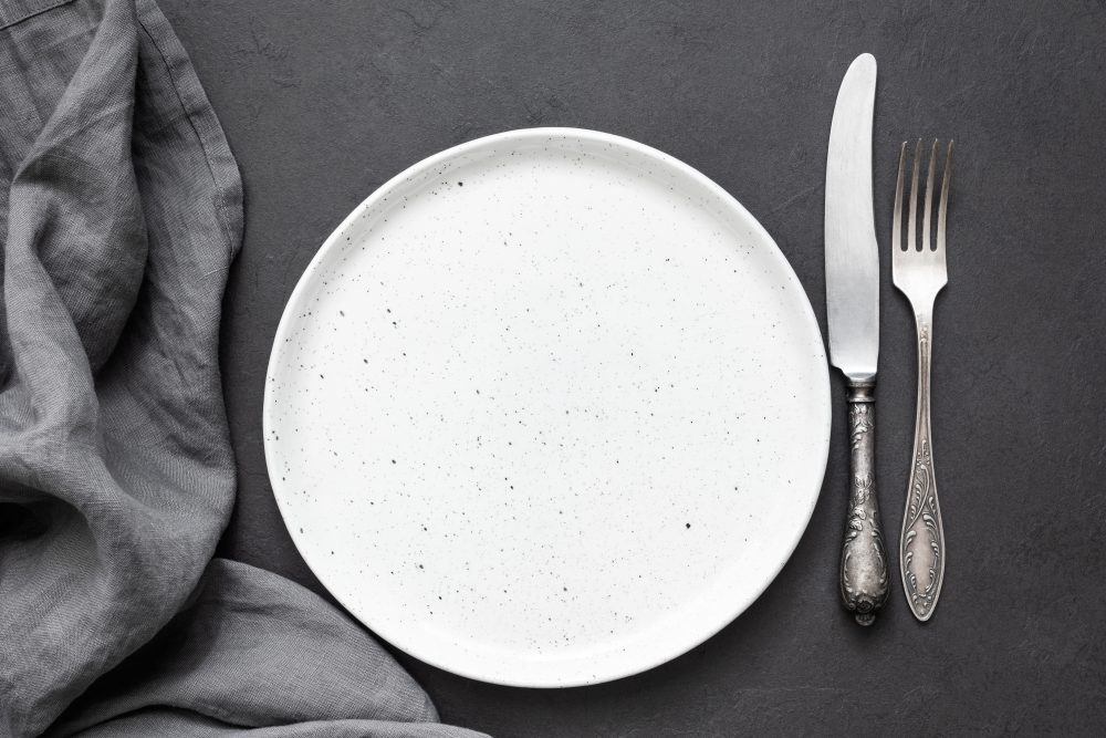 Vintage cutlery or silverware, empty plate and kitchen textile napkin. Top view, copy space for text