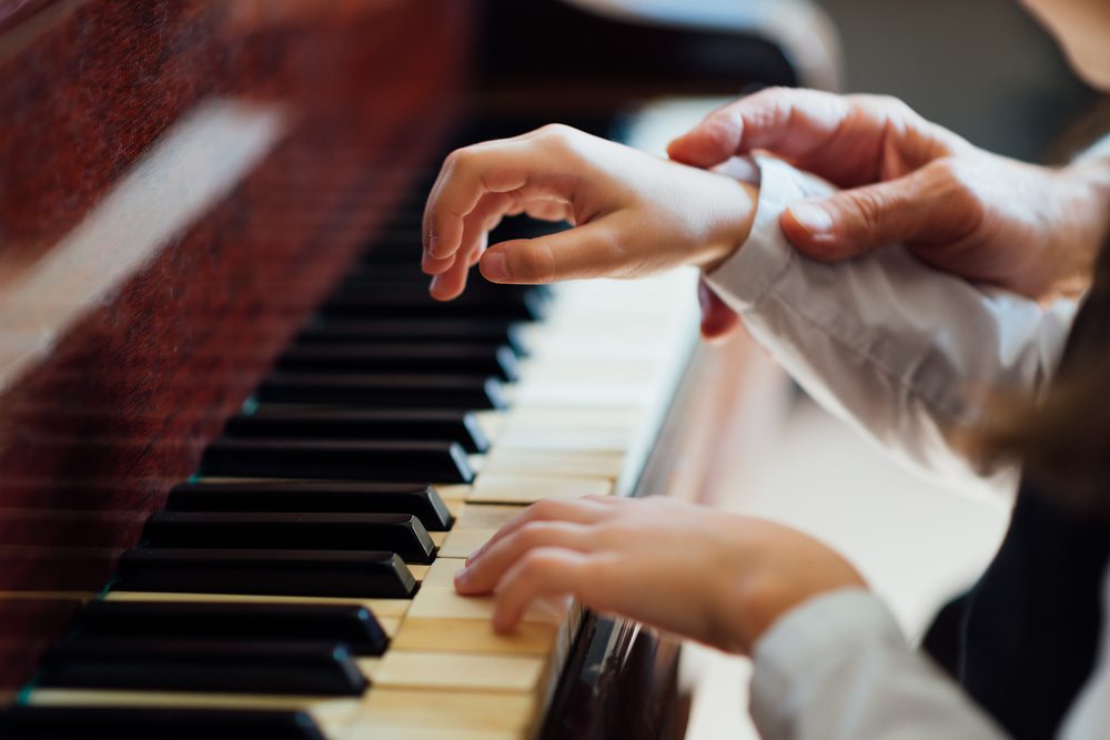 experienced master piano hand helps the student, close-up