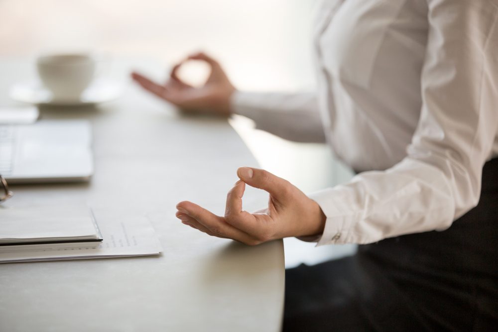 Office meditation for reducing work stress relief concept, female hands in mudra close up view, business woman practicing yoga at workplace for mindfulness development. mental health and balance