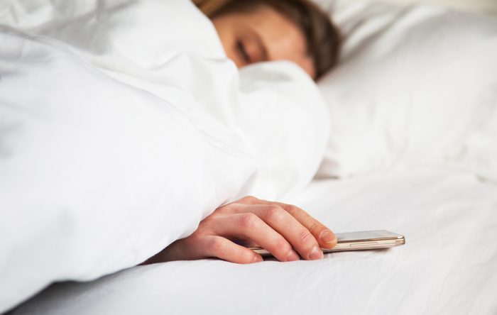 woman sleeping in bed being woken by mobile phone