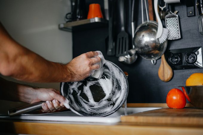 washing dishes. male hands in foam washes the frying pan with a detergent and sponge in the kitchen of the house.