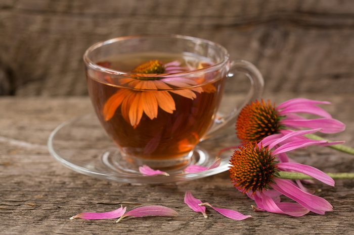 Glass mug of echinacea tea next to echinacea flower 