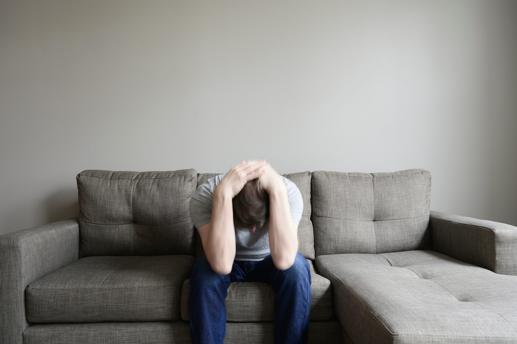 depressed man sitting on couch with head in lap